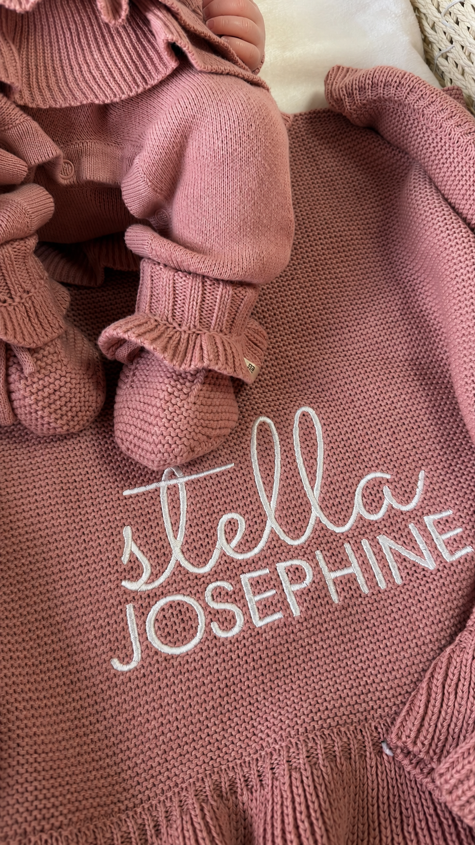 Mauve ruffle newborn booties displayed on the personalized knit blanket embroidered with Stella Josephine.