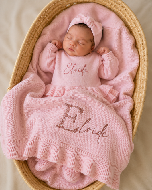 Newborn lying on side wearing personalized petal pink Ballerina romper with embroidered name, short style