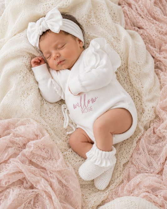 Newborn wearing personalized warm white Butterfly romper with bow and booties, close angle