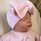Close-up of a newborn wearing an oversized petal pink bow headwrap and personalized Ballerina knit romper.