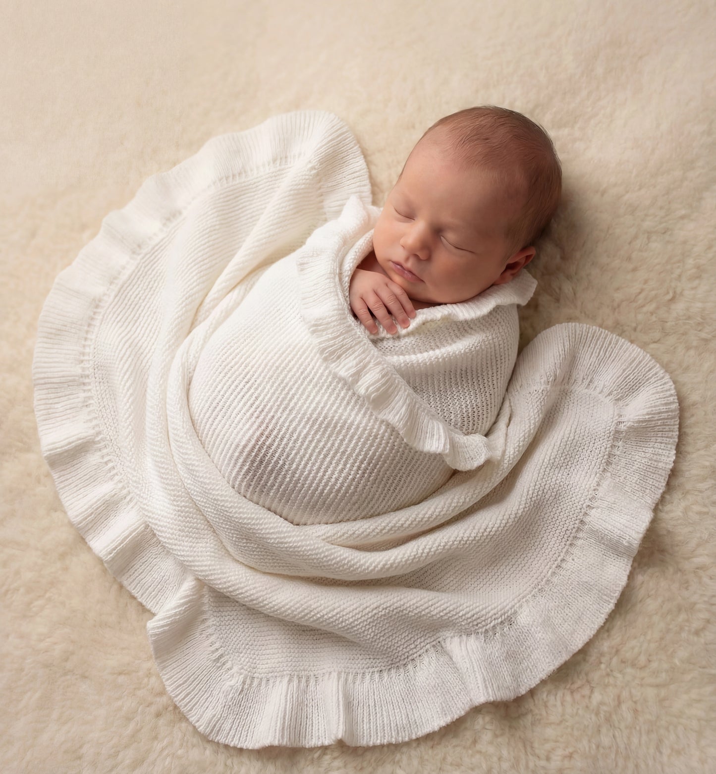 Newborn swaddled in personalized ballerina knit baby blanket with ruffled trim detail