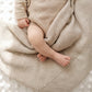 Close-up of classic knit baby blanket in soft khaki cotton showing textured weave and draped detail with newborn