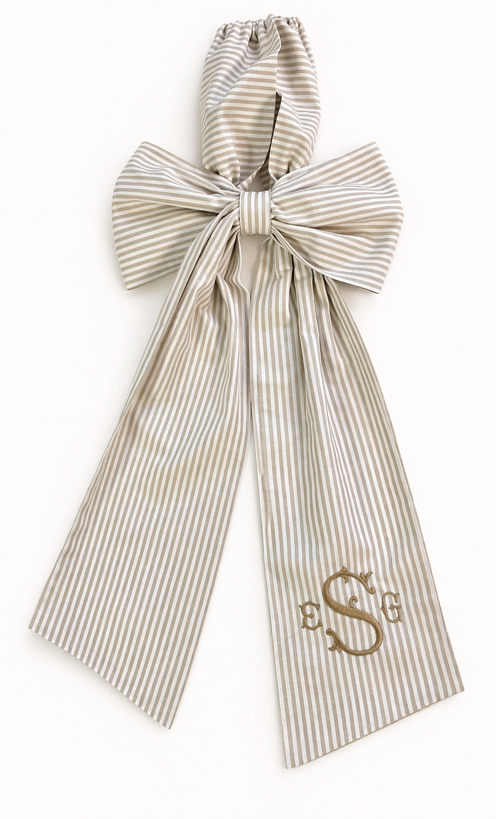 Personalized striped newborn sash with oversized bow and embroidered monogram shown in flat lay on white background