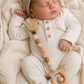 Newborn baby wearing a personalized pacifier clip with name beads and wooden teether, a practical and thoughtful baby essential