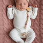 Personalized pacifier clip with name beads on newborn baby girl lying on a pink knit blanket