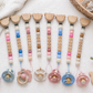 Set of custom colorful baby pacifier clips with beads on a light background