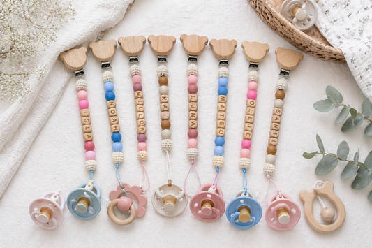 Set of custom colorful baby pacifier clips with beads on a light background