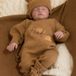 Newborn in a personalized Teddy Brown kimono romper and bear-ear hat, resting on the matching embroidered knit blanket