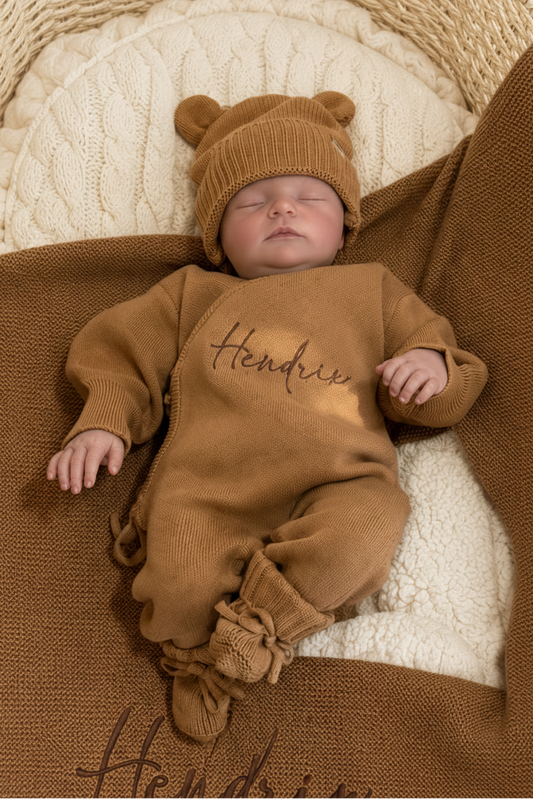 Newborn in a personalized Teddy Brown kimono romper and bear-ear hat, resting on the matching embroidered knit blanket