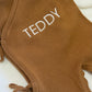 Close-up of personalized name embroidery on a Teddy Brown newborn knit romper