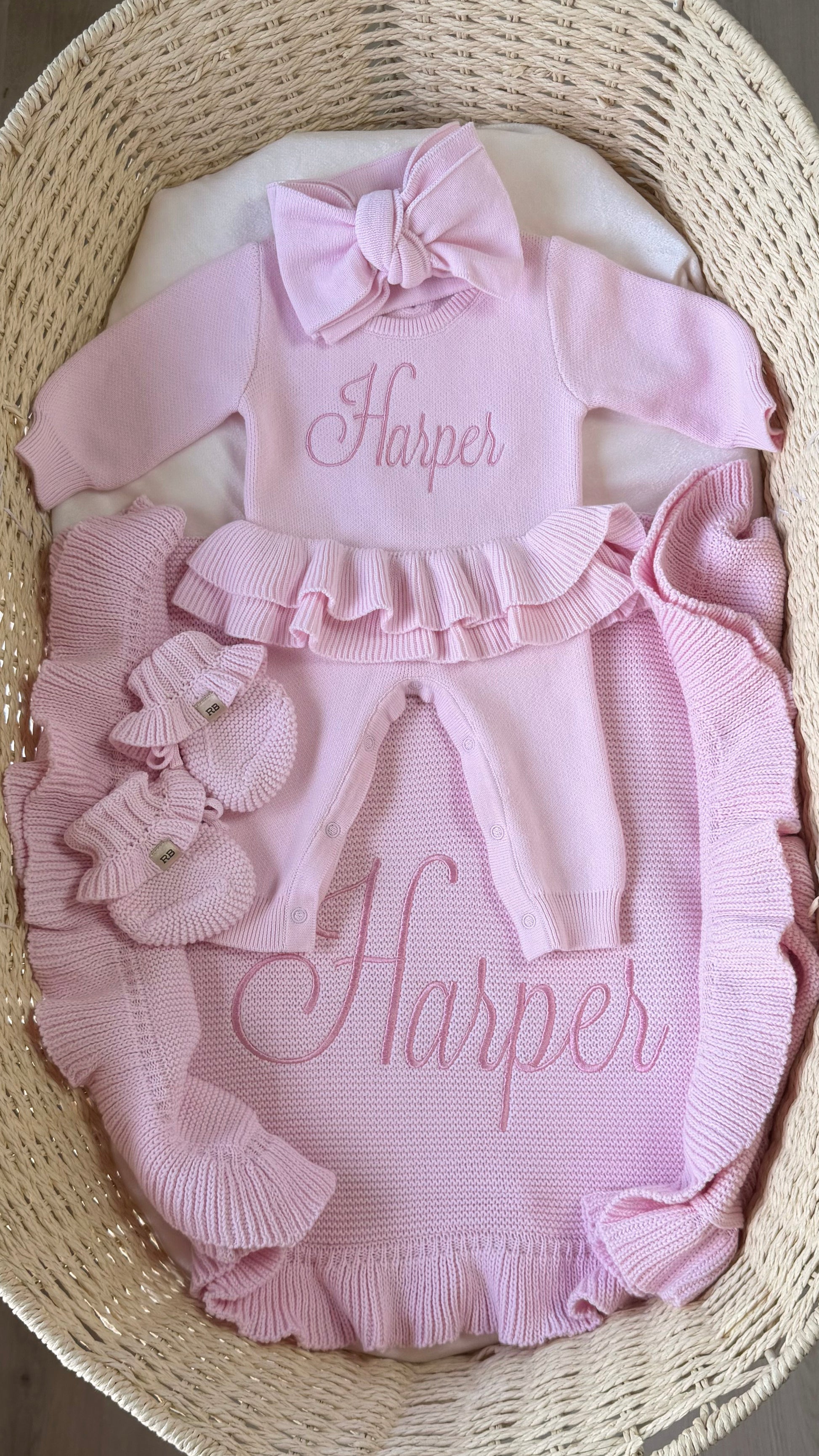 Personalized petal pink Ballerina long romper set arranged with a matching bow, ruffle booties and ruffle knit blanket.