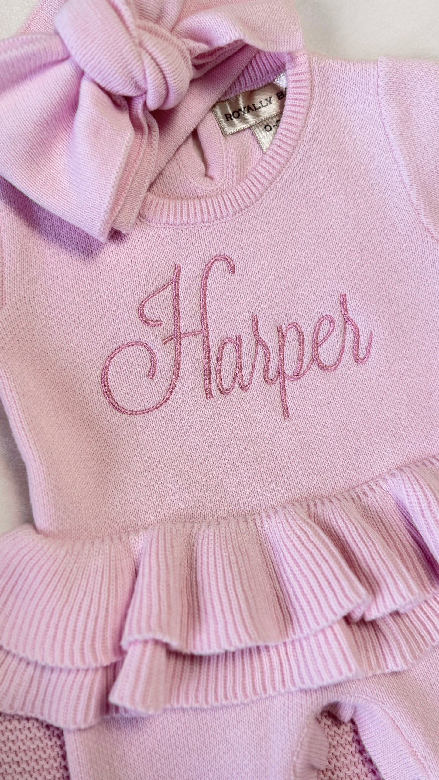 Close-up of Harper name embroidery and layered waist ruffle on the petal pink Ballerina long romper.