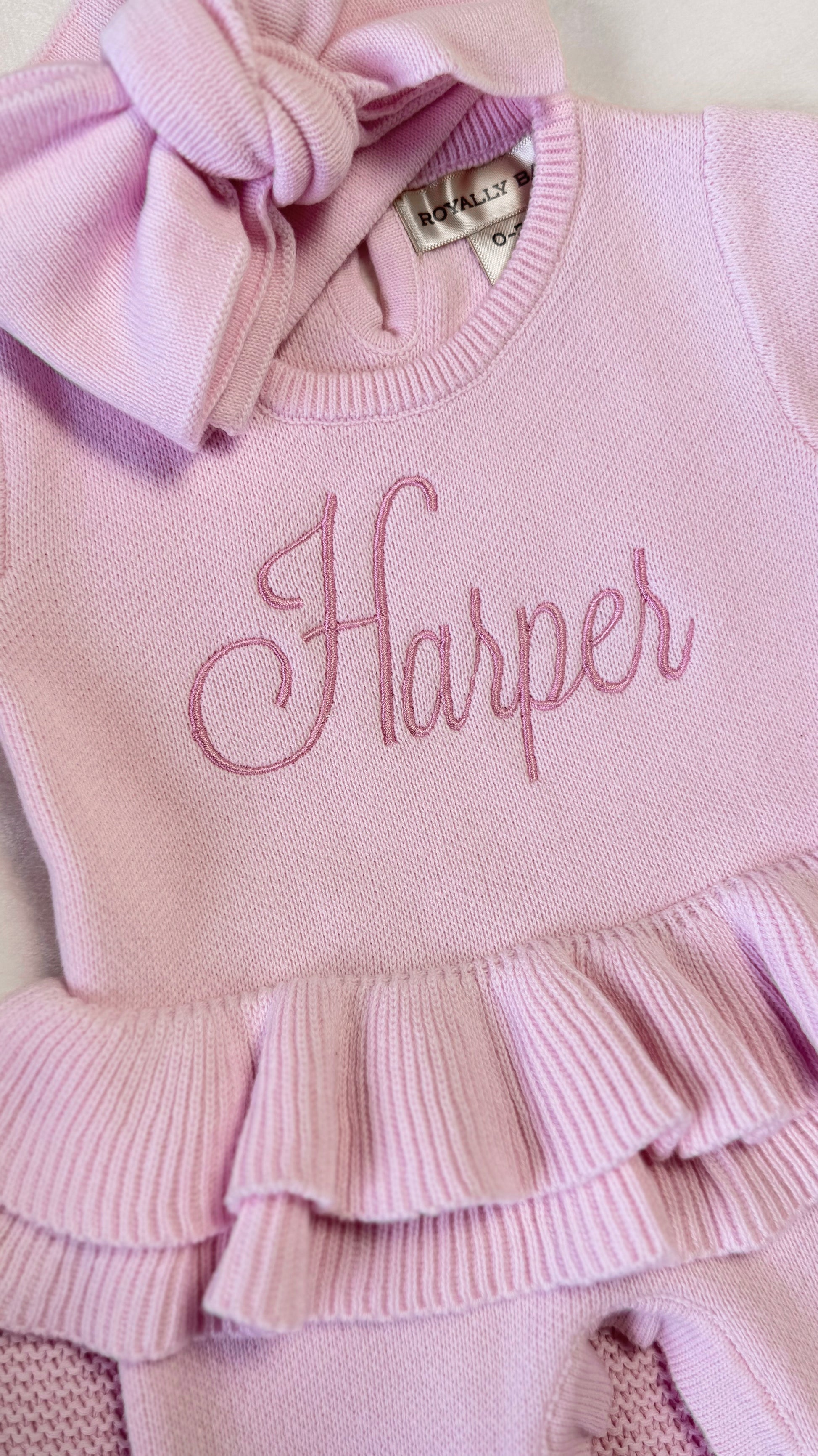 Close-up of Harper name embroidery and layered waist ruffle on the petal pink Ballerina long romper.