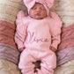 Newborn wearing a personalized petal pink Butterfly romper set with matching bow and ruffle booties.