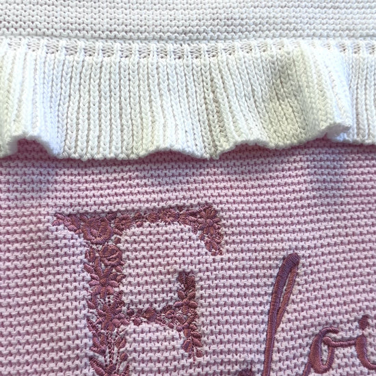 Video of personalized floral initial baby blanket with embroidered name and soft ruffled trim in knit cotton