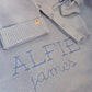 Close-up of the personalized Baby Blue Classic Knit romper and matching blanket embroidered with the name Alfie James.