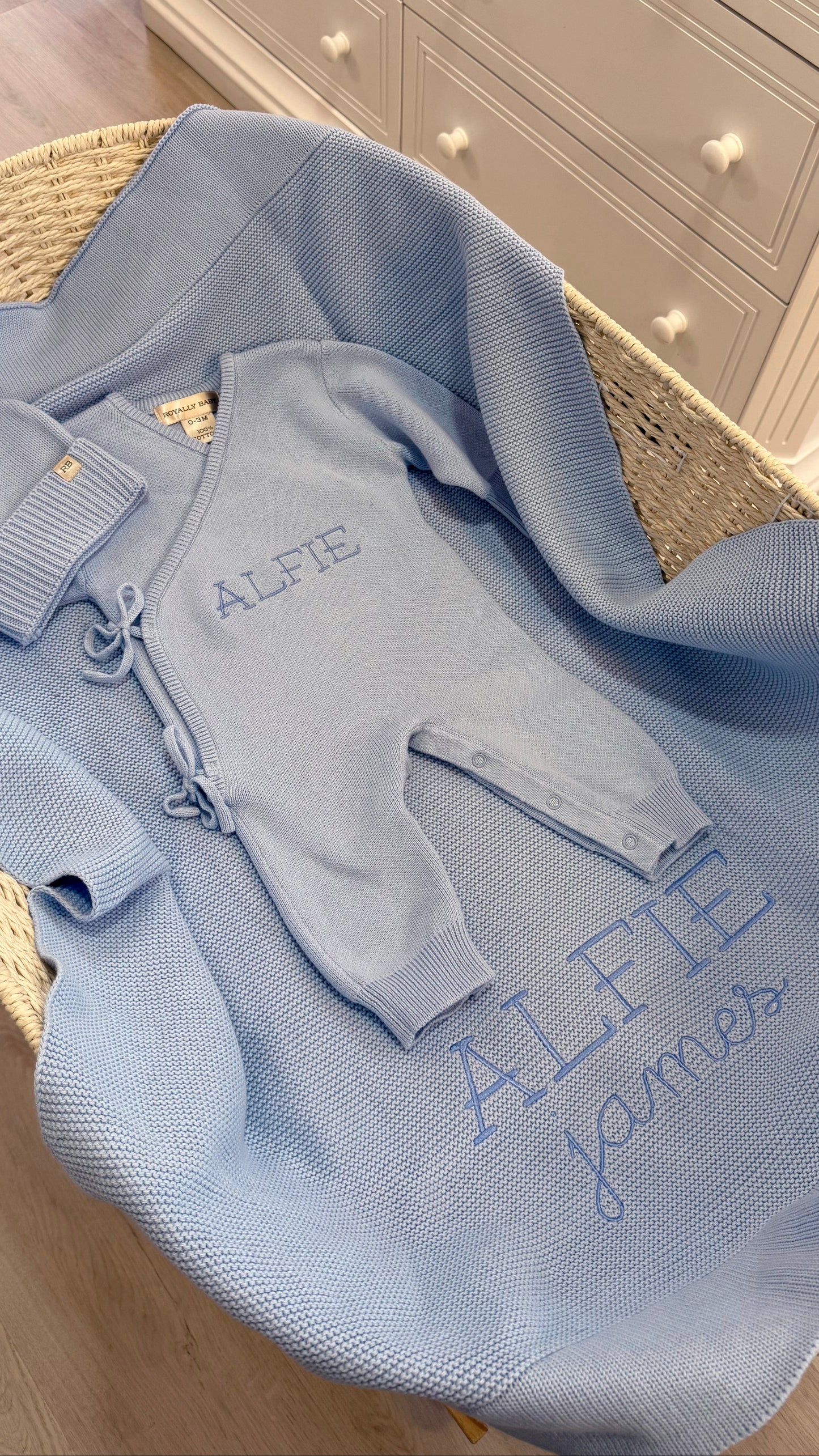 Baby Blue Classic Knit long romper set displayed with its matching newborn hat, booties and personalized knit blanket.