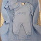 Personalized Baby Blue Classic Knit long romper set with matching hat and booties arranged on an Alfie embroidered knit blanket