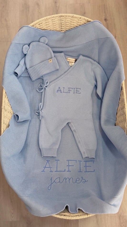 Personalized Baby Blue Classic Knit long romper set with matching hat and booties arranged on an Alfie embroidered knit blanket