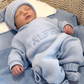 Sleeping newborn wearing the personalized Baby Blue Classic Knit long romper with matching knit hat and booties on an Alfie embroidered blanket.