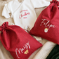 Personalized Christmas gift sack flat lay in deep red woven fabric with embroidered name