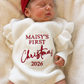 Newborn portrait wearing a personalized romper embroidered Maisy's First Christmas