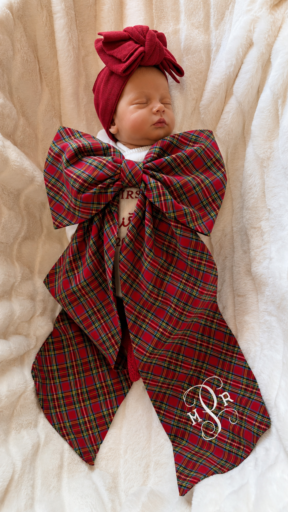 Sleeping newborn wrapped in a personalized plaid tartan Christmas sash with monogram