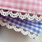 Close-up of lace gingham applique monogram embroidery on a newborn bow sash