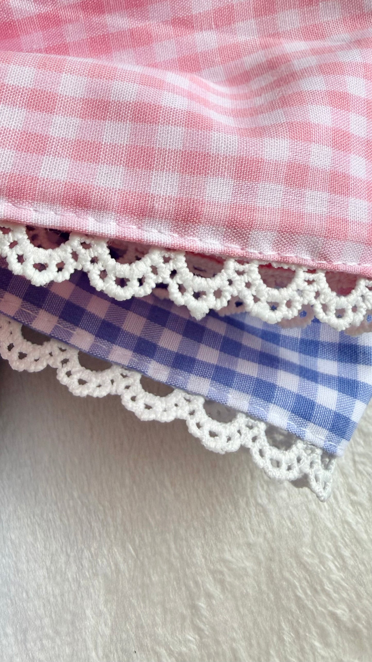 Close-up of lace gingham applique monogram embroidery on a newborn bow sash