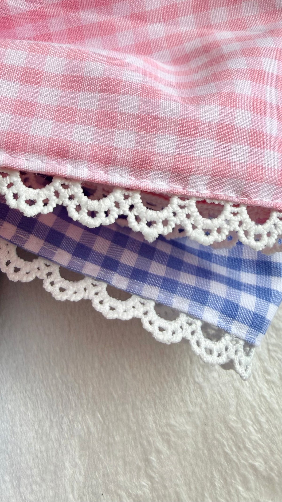 Close-up of lace gingham applique monogram embroidery on a newborn bow sash