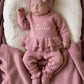 Newborn wearing the personalized Dusty Mauve Ballerina long romper beside a matching ruffle blanket embroidered with Stella Josephine.