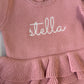 Close-up of Stella name embroidery and layered waist ruffle on the Dusty Mauve Ballerina long newborn romper.