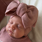 Close-up of a newborn wearing the oversized Dusty Mauve knit bow and personalized Stella Ballerina long romper.