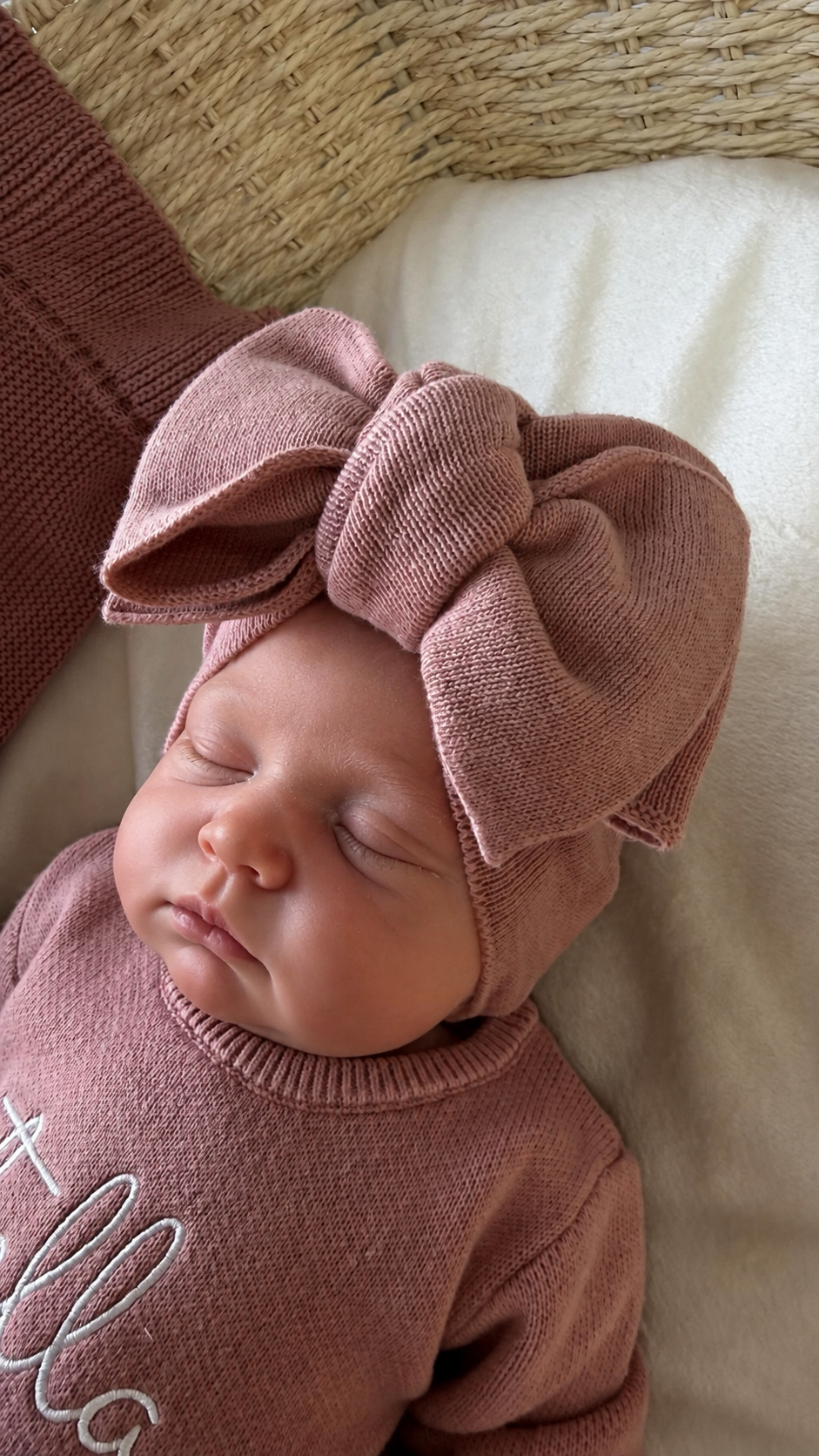 Close-up of a newborn wearing the oversized Dusty Mauve knit bow and personalized Stella Ballerina long romper.