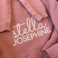 Close-up of Stella Josephine name embroidery on the personalized Mauve ruffle knit newborn blanket.