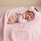 Newborn baby lying on personalized ballerina knit blanket with embroidered name and soft ruffled trim