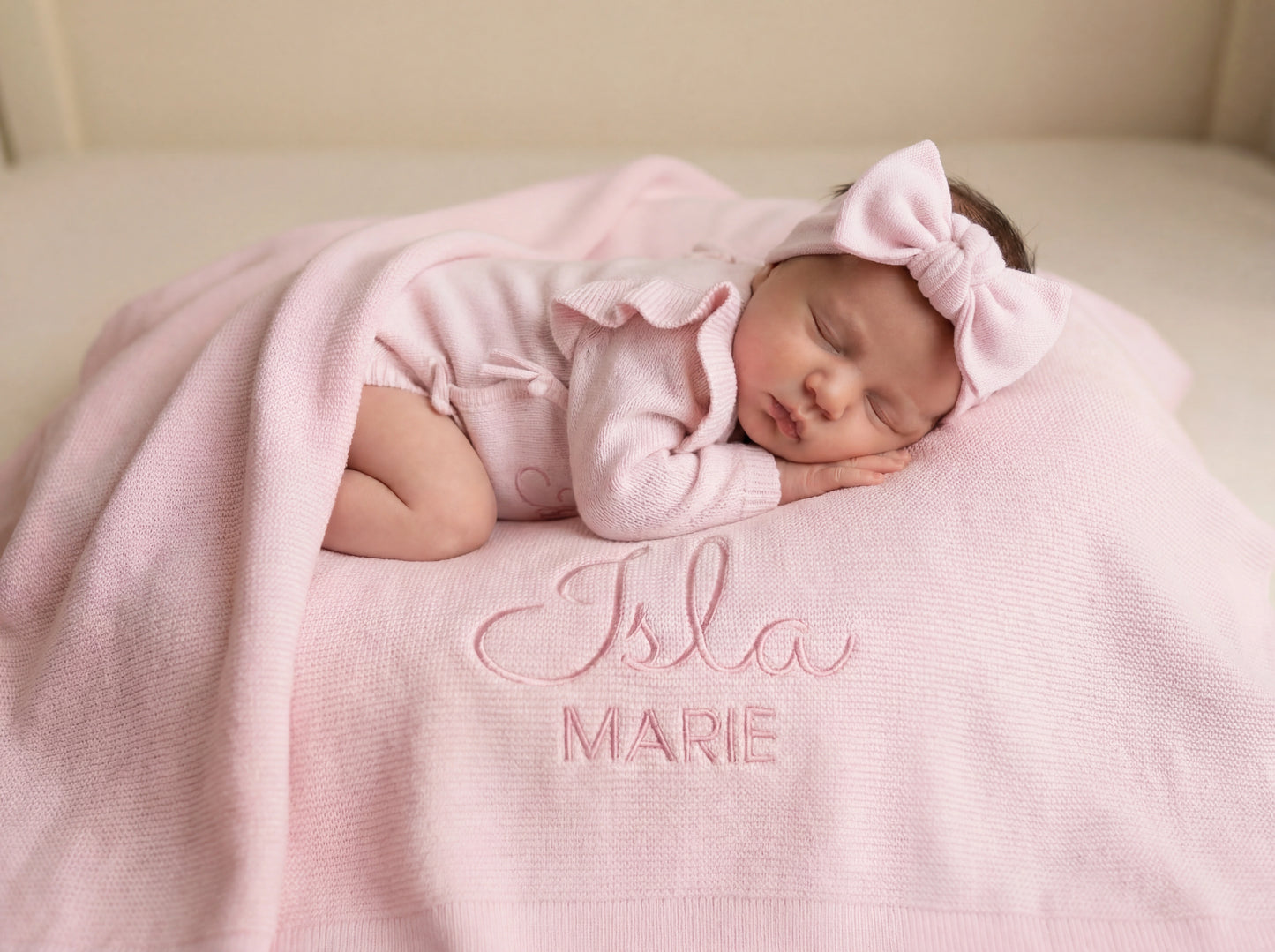 Newborn baby lying on personalized ballerina knit blanket with embroidered name and soft ruffled trim