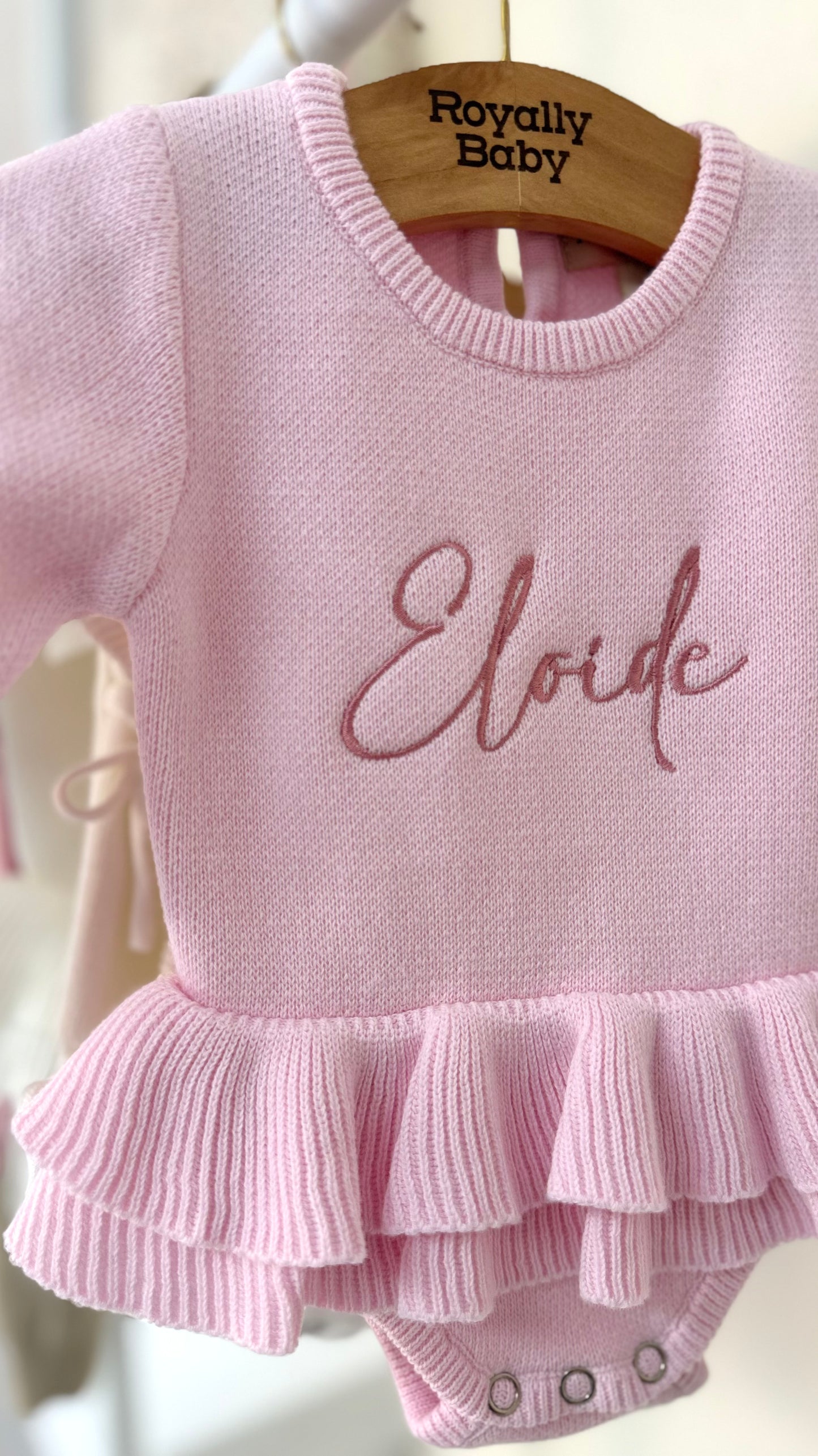 Detailed view of embroidered name on personalized Petal Pink ballerina baby romper showing soft knit fabric and ruffle trim