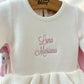 Detailed view of embroidered name on personalized Soft Ivory ballerina baby romper showing soft knit texture and ruffle trim