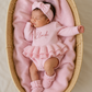 Side angle view of newborn wearing personalized petal pink Ballerina romper with ruffle booties