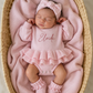 Newborn wearing personalized petal pink Ballerina romper, short style, with embroidered name and matching bow and booties