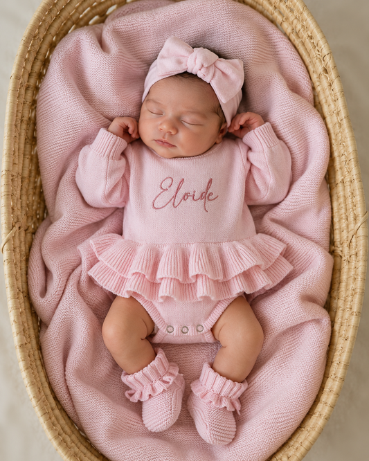 Newborn wearing personalized petal pink Ballerina romper, short style, with embroidered name and matching bow and booties