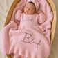 Newborn lying on side wearing personalized petal pink Ballerina romper with embroidered name, short style