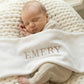 Newborn wearing classic knit wrap romper in soft khaki with personalized embroidery, styled flat lay