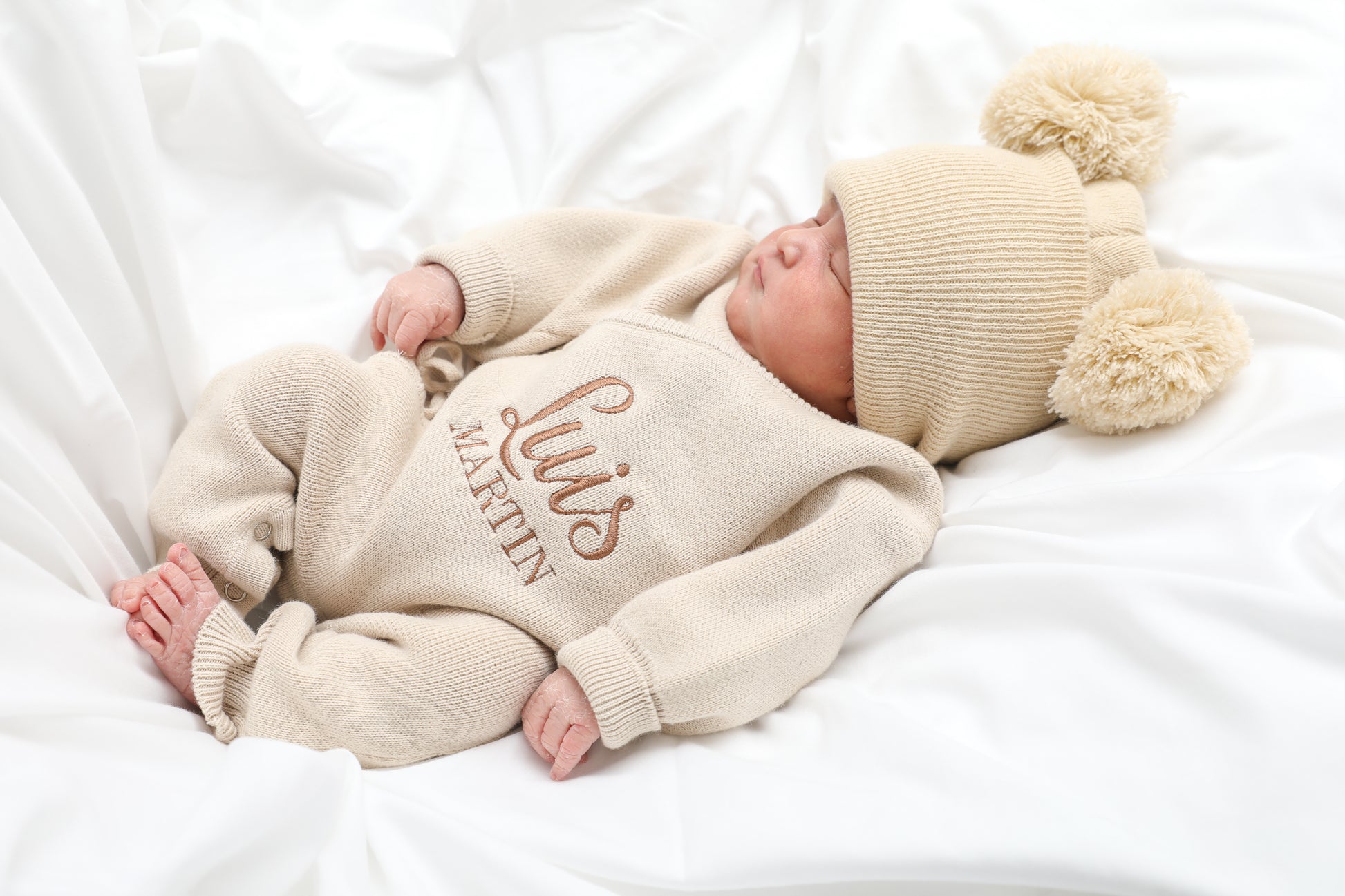 Newborn baby wearing classic knit wrap romper in soft khaki with personalized embroidery and knit hat