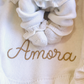 Newborn wearing the Warm White Ballerina long romper on a personalized Amora knit blanket