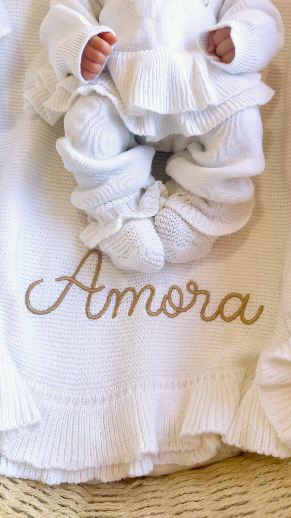Newborn wearing the Warm White Ballerina long romper on a personalized Amora knit blanket