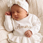 Newborn wearing the personalized Warm White Ballerina long romper with oversized bow on a ruffle knit blanket
