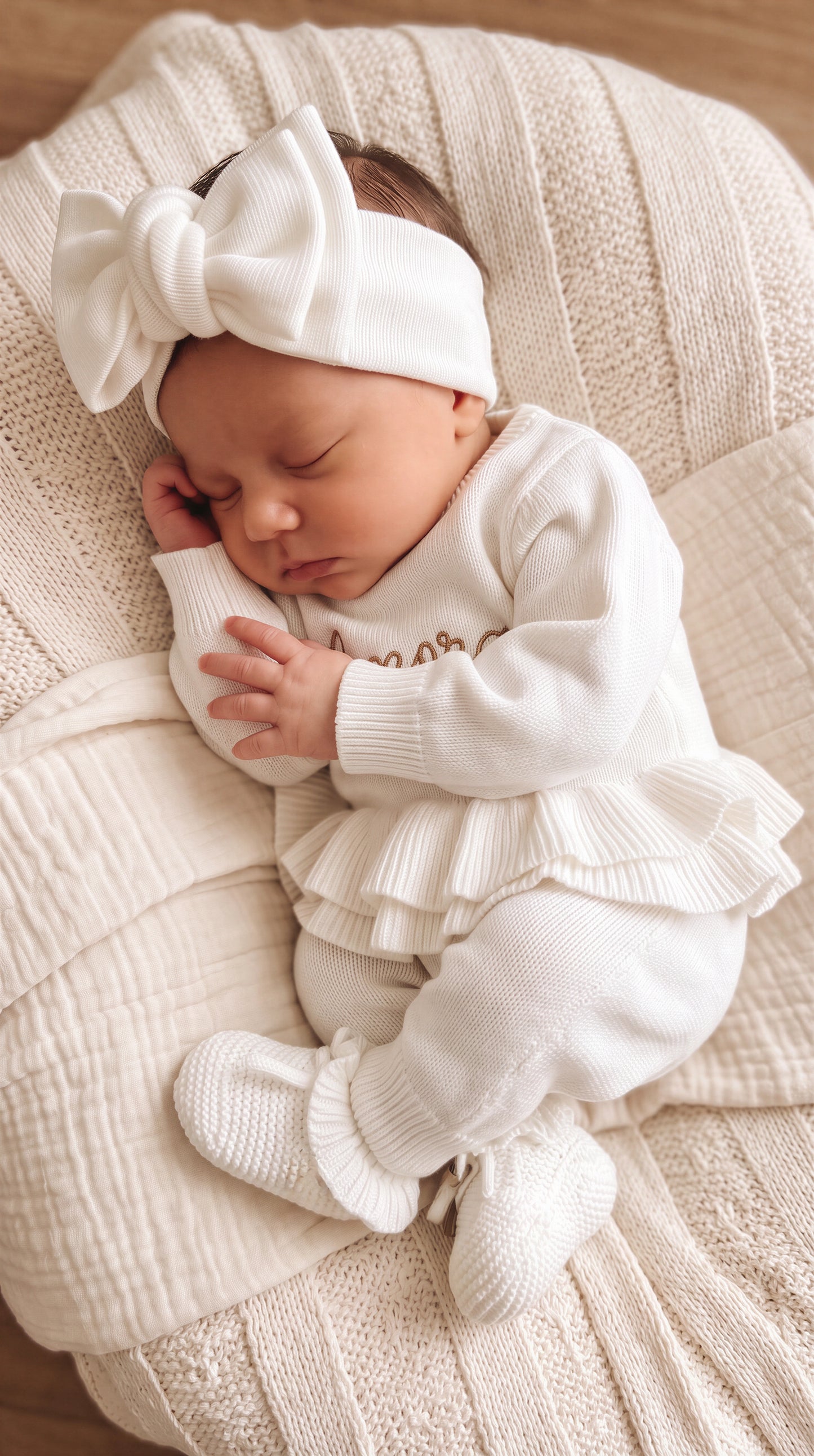 Sleeping newborn in the personalized Warm White Ballerina long romper and matching oversized bow.