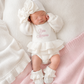 Newborn wearing personalized warm white Ballerina romper, short style, with embroidered name and matching bow and booties